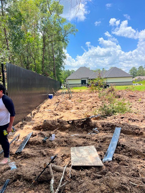 Black metal fence installation progress in yard